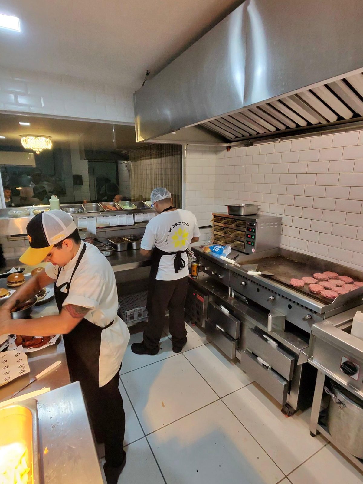 Cozinha do salão com chapa e equipe montando burgers